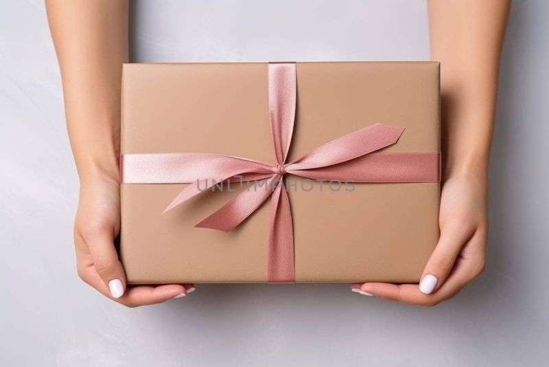 Caja de regalo de joyería con lazo rosa en manos femeninas.